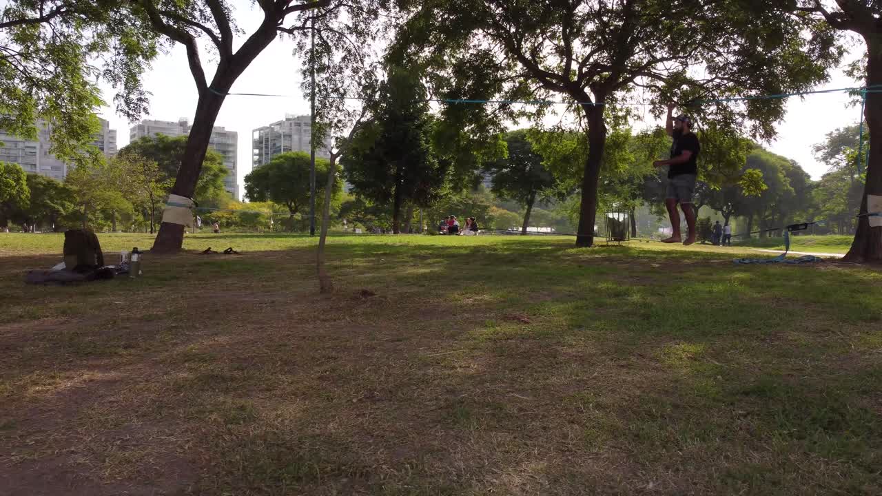 hombre practicando el equilibrio en la línea floja del parque vicente lópez durante el día soleado - buenos aires - órbita primer plano
