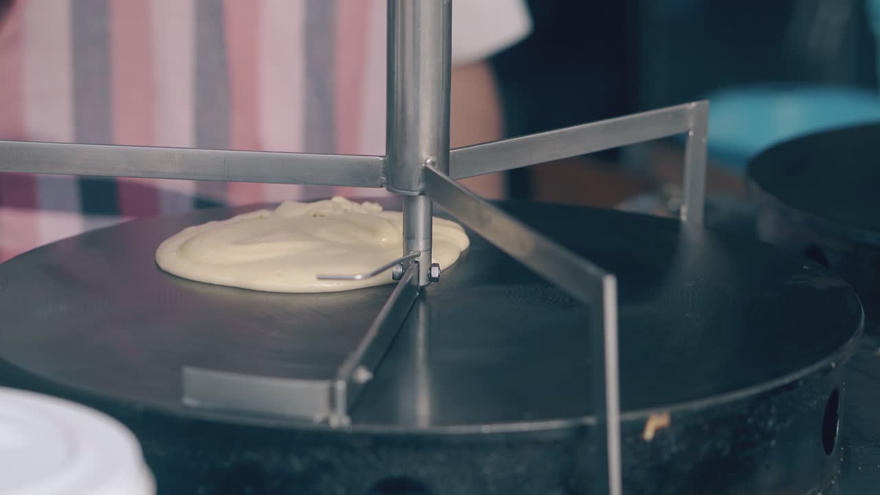 cooker puts dough on hot stove and spreads with turning tool