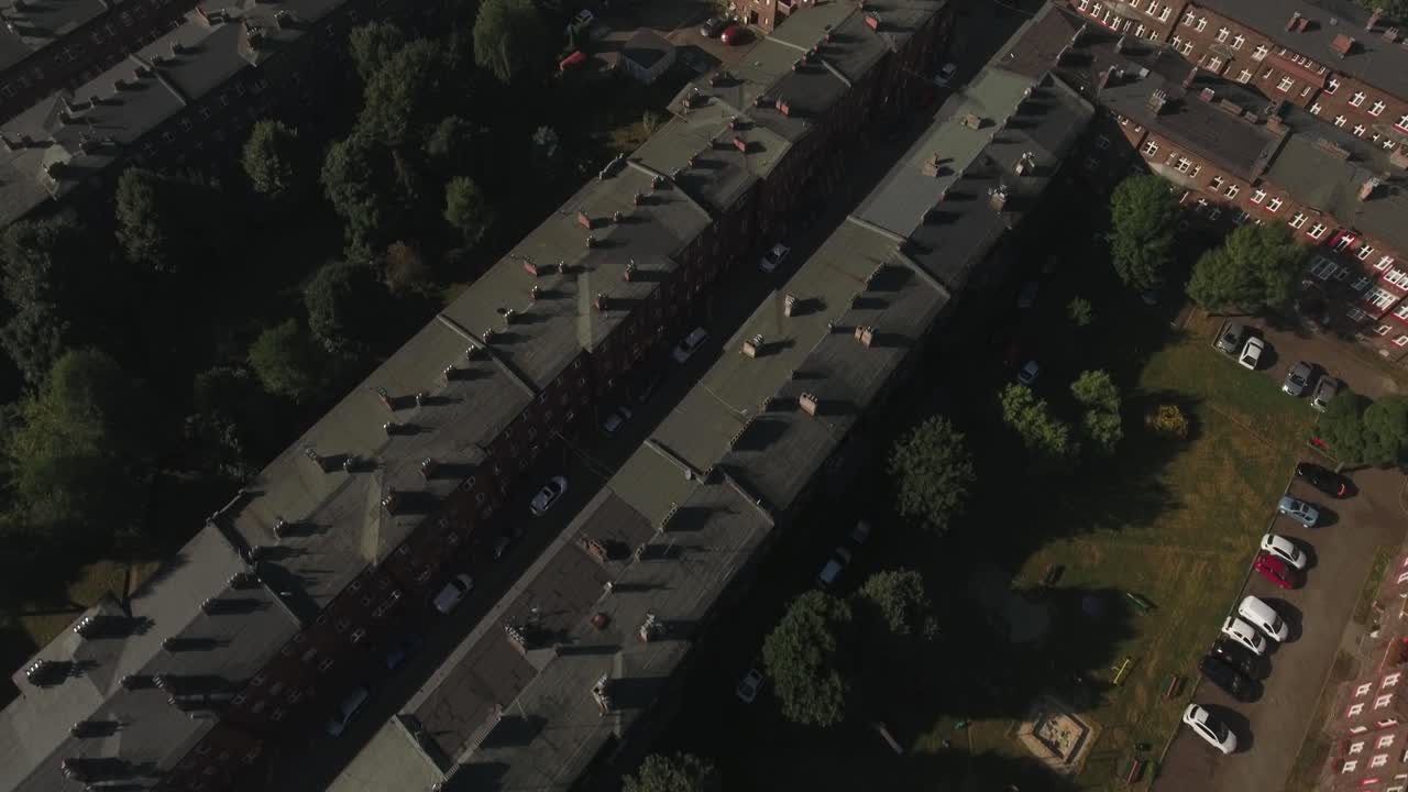 실레시아의 역사적인 노동자 정착촌의 역동적인 드론, 주택 건물, 굴을 가진 지붕, 그리고 배경에 큰 공장을 특징으로합니다.