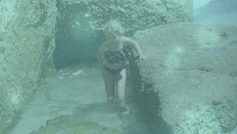 glowing blue spots of light against caucasian girl walking close to the rocks near the sea