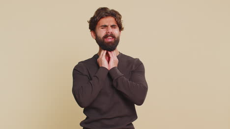 unhealthy lebanese young man coughing covering mouth with hand feeling sick over beige background