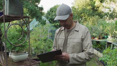 Jardinero-Masculino-De-Raza-Mixta-Tomando-Notas-En-El-Centro-De-Jardinería