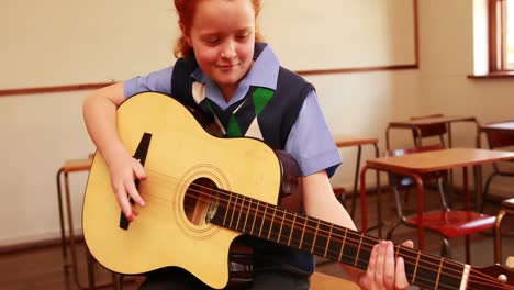 cute pupil playing guitar in classroom