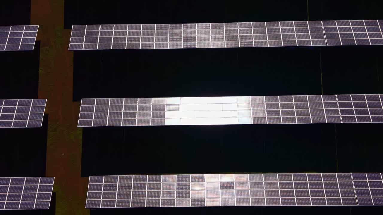 Pannelli solari disposti in linee parallele su una superficie piana che riflettono la luce solare a mezzogiorno in un parco solare