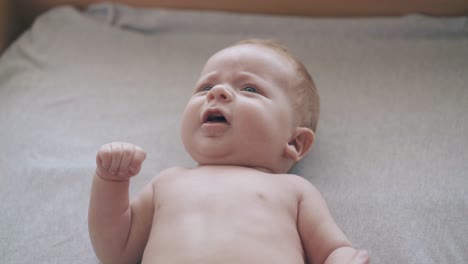 newborn son lies on baby table and nurse performs massage