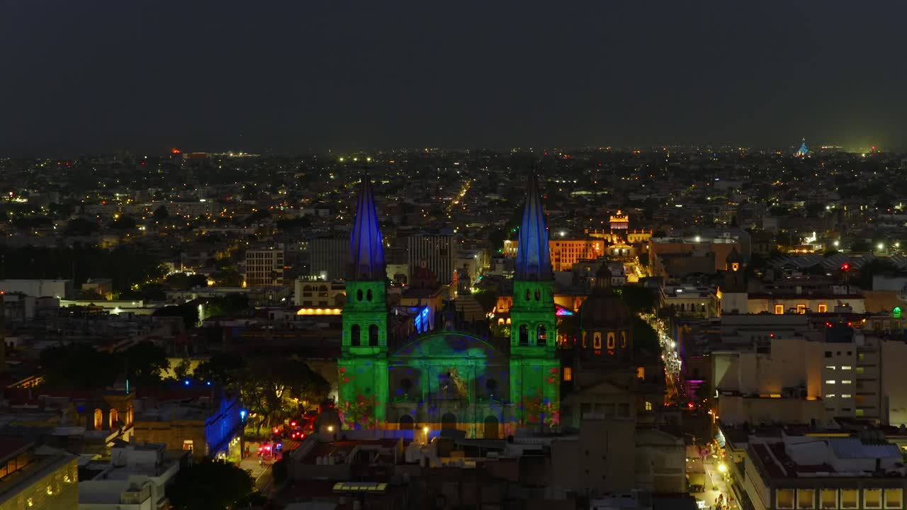 Catedral de Guadalajara illuminated by vibrant light projections celebrating Jalisco traditions and cultural icons at Aluzinante light sow. Dolly in nighttime aerial