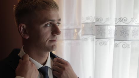 handsome groom fixes his jacket. wedding morning. businessman. slow motion