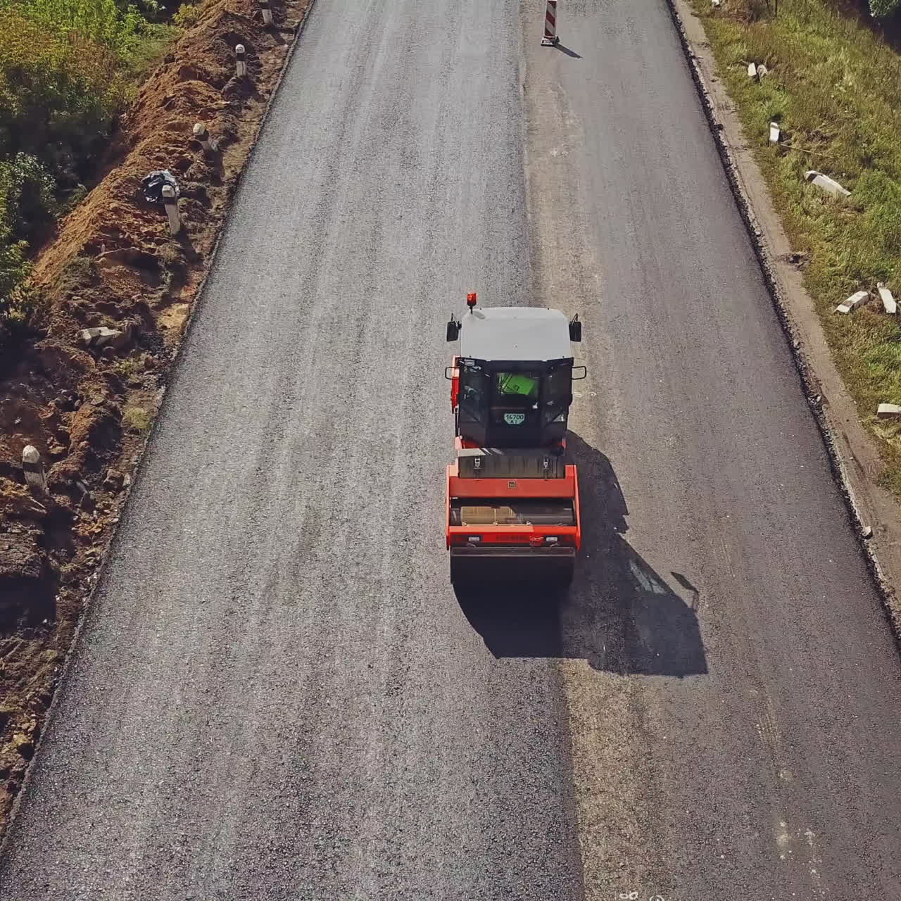 Large road-roller paving a road. Road construction. Aerial view.
