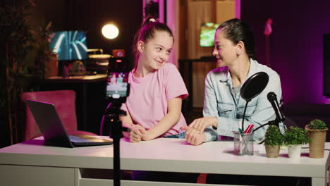 Cute-kid-and-mom-recording-family-vlog-in-apartment-studio-with-pink-neon-lighting