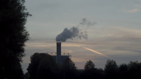 chimenea de fábrica de humo contaminante contra una puesta de sol