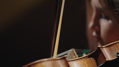 vista de cerca del violín y el rostro de una joven músico está tocando el violín en la escuela de música