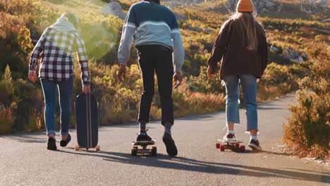 happy diverse skater friends high five together enjoying summer vacation longboarding on countryside road cruising dowhill using skateboard