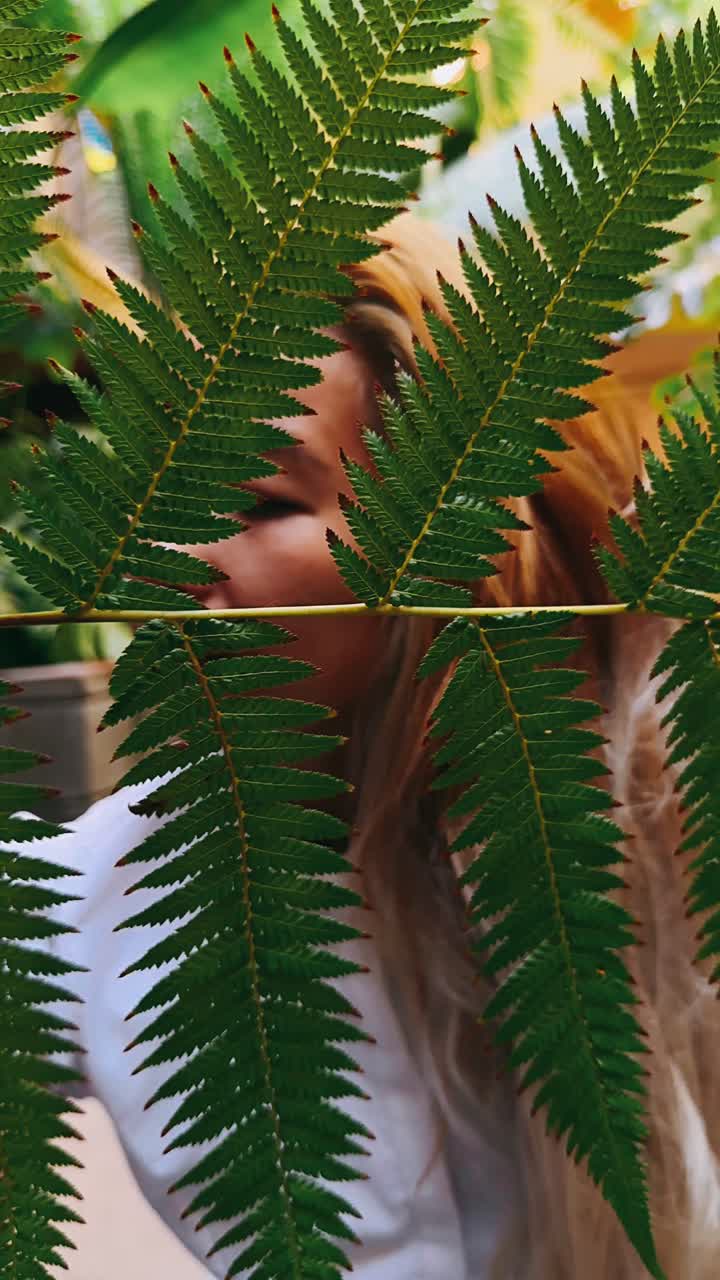 mujer en un invernadero rodeado de helechos
