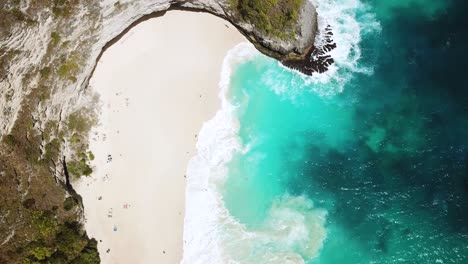 drone shot gliding over the beautiful kelingking beach with it's turquoise-blue water and large waves crashing on the shore