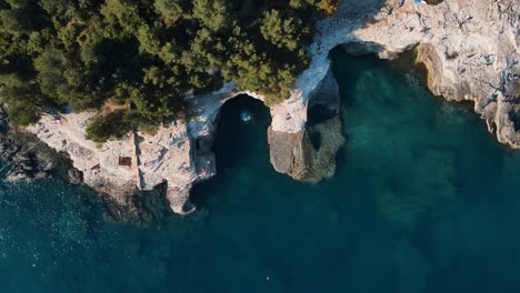 a down wards pulling out drone shot of tourists enjoying themselves -galebijana cave pula