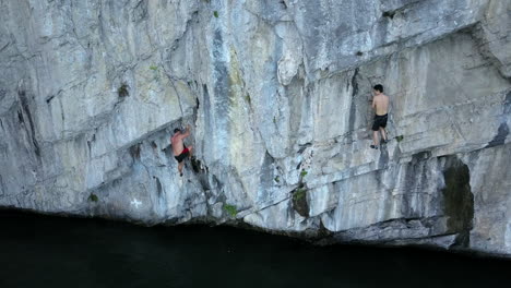 aerial shot of two young mean free climbing the side of a sharp cliff in halong bay,vietnam