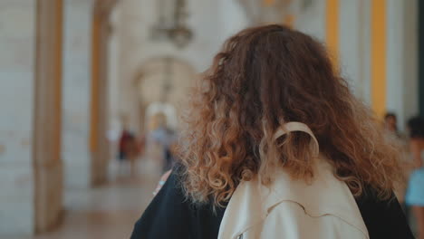 woman walking through a historic hallway