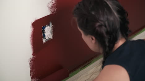 Young-woman-paints-red-wall-in-house