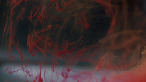 abstract shot of red ink slowly moving in an transparent liquid on a dark background