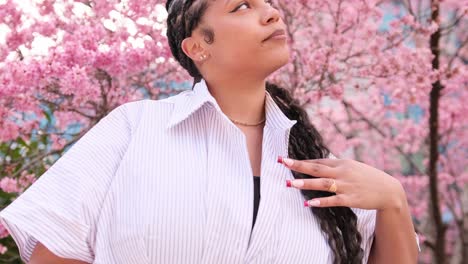 darkskinned african american woman in a white shirt against a background of pink sakura portrait of a darkskinned african american woman in a white shirt against a background of pink sakura posing for the camera european darkskinned woman against a background of pink sakura blossom