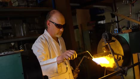 Side-view-of-mature-male-worker-blowing-glass-in-glass-factory-4k