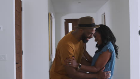 smiling african american couple talking and laughing in hall at home