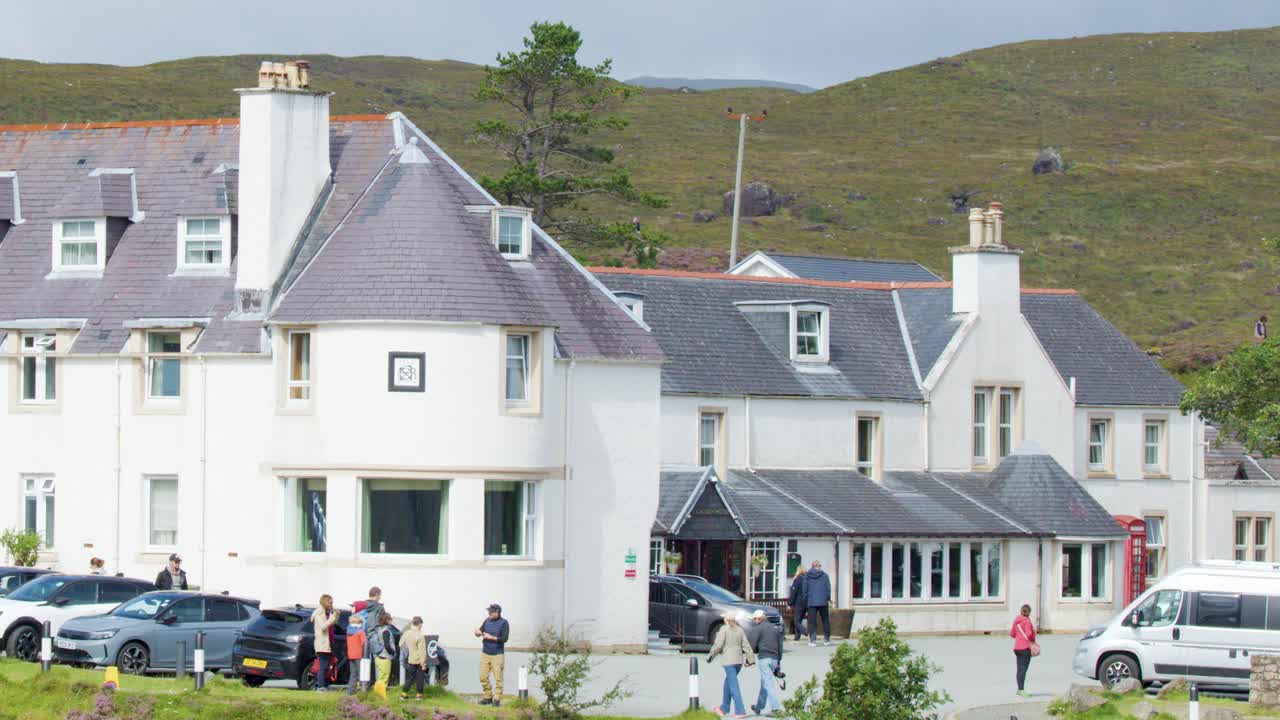 Guests gather outside a white clubhouse hotel in Edinburgh, Scotland, on a sunny day