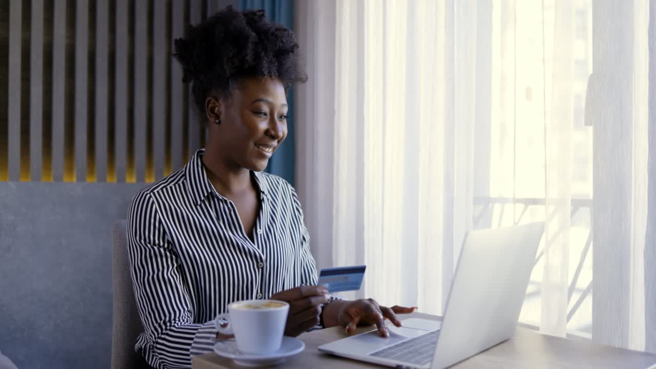 Wide image of young black woman busy holding her credit card