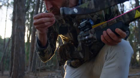 man aiming with compound bow in the forest 4k