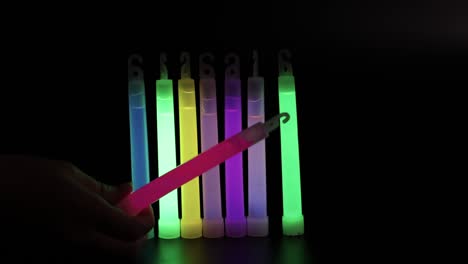 hand holding a variety of colorful glow sticks