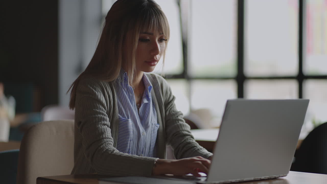 Young Asian attractive female office worker sitting at the laptop computer at the desk working and thinking.