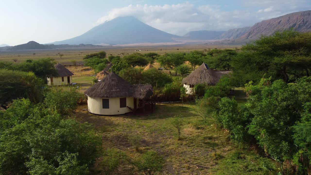 un bonito dron volando sobre las copas de los árboles y un pueblo africano con una vista impresionante del volcán ol doinyo lengai en el fondo en tanzania en el norte de áfrica