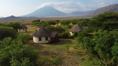 A-nice-drone-shot-flying-over-the-tree-tops-and-an-African-village-with-a-stunning-view-of-Ol-Doinyo-Lengai-volcano-in-the-background-in-Tanzania-in-North-Africa