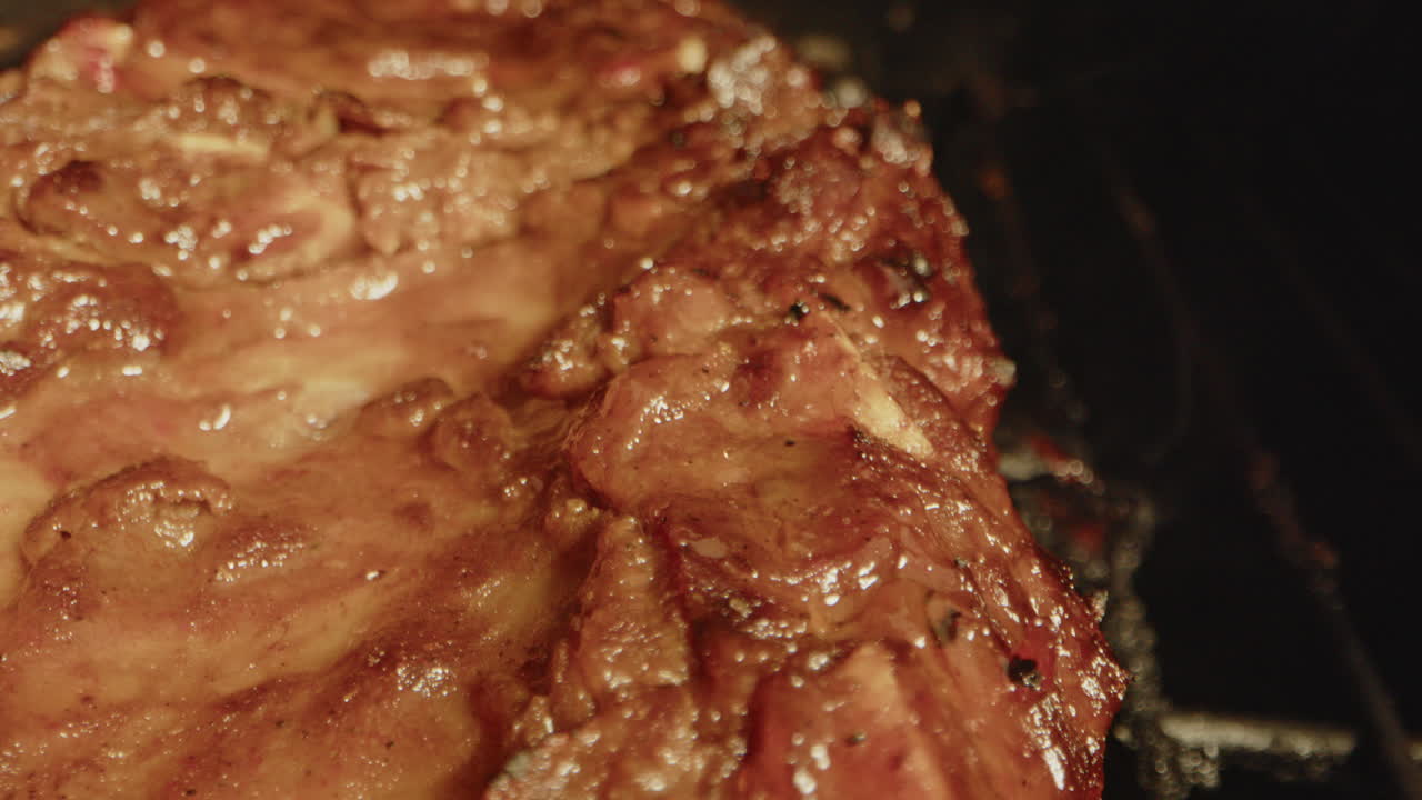 Beautiful macro of spareribs slowly being grilled on a barbecue with smoke rising from the meat