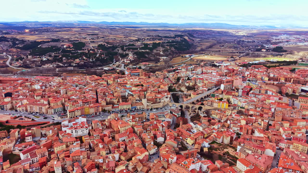 Veduta di una grande città spagnola con numerosi edifici e strade, sotto un cielo sereno, scattata da un punto panoramico durante il giorno.