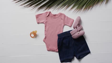 video of pink baby grow, shorts, dummy and pink booties with copy space on white background