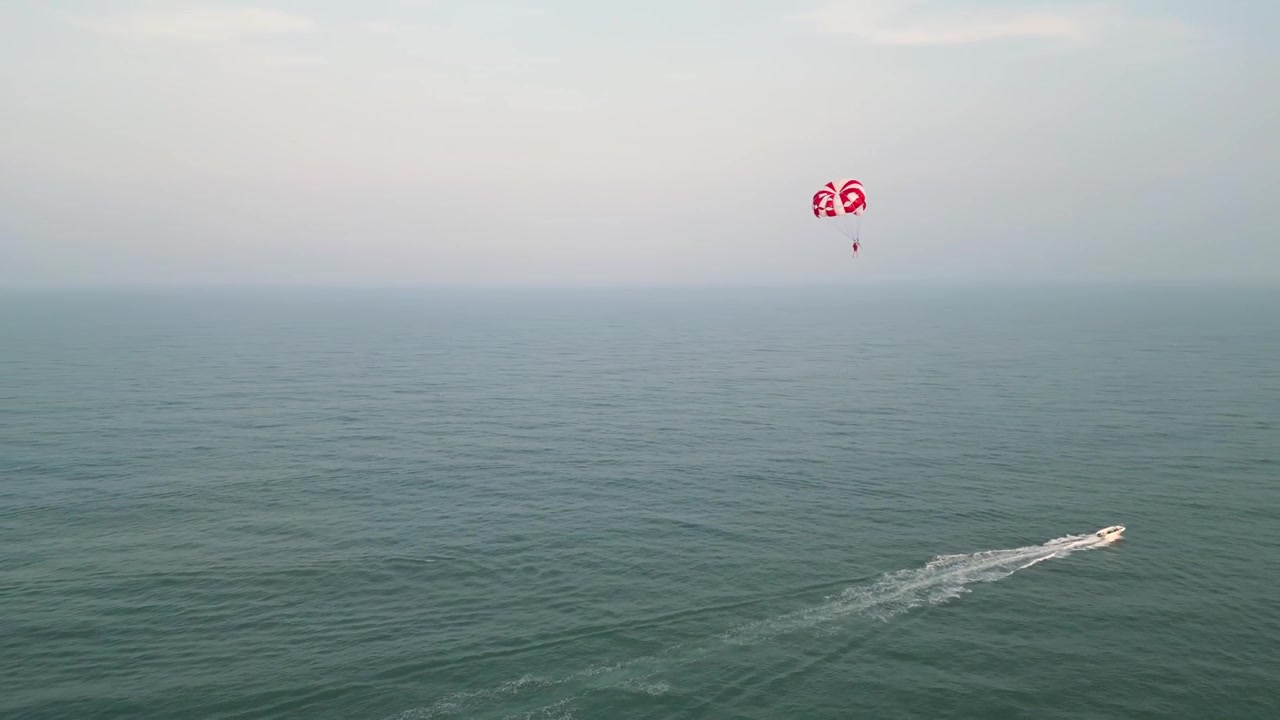 Video shot of people parasailing in the sea of ​​Da Nang, with the sea and the hazy sky merging into the horizon in the background.
