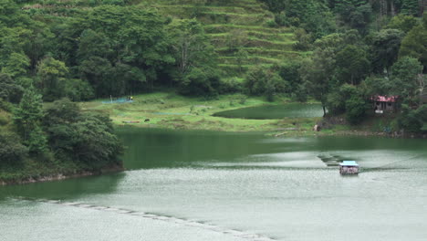 a beautiful green lake with the terraced fields of the himalaya foothills above