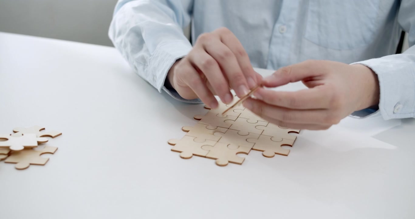 Goditi l'arte di assemblare puzzle mentre le mani uniscono con cura i pezzi in un ambiente interno.