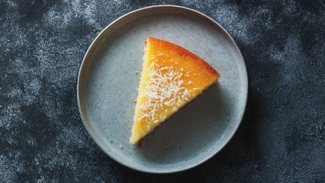 slice of cassava cake on rustic plate with coconut topping