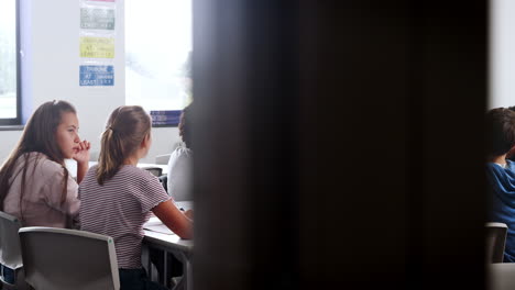 female high school tutor standing by table with students teaching lesson