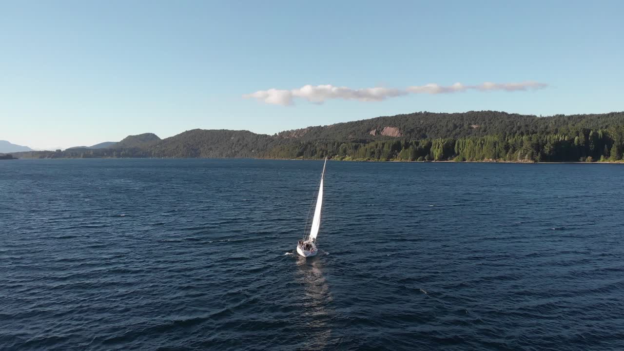antena en órbita de un velero blanco navegando en un lago patagónico azul oscuro