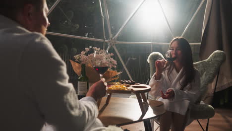 couple enjoying wine and snacks in a transparent dome