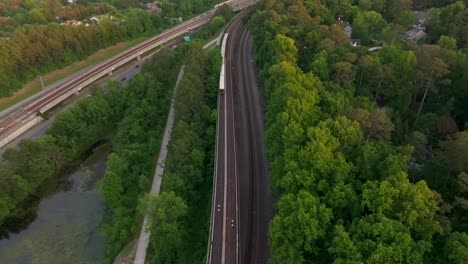 drone shot of atlanta metro rail crossing through natural park trails of buckhead neighbourhood, georgia state route 400, t harvey mathis parkway