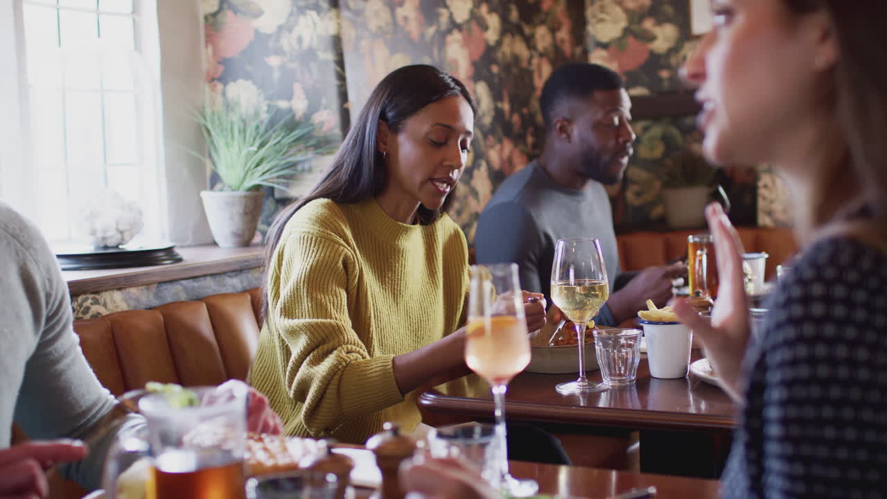 Group Of People Eating In Restaurant Of Busy Traditional English Pub