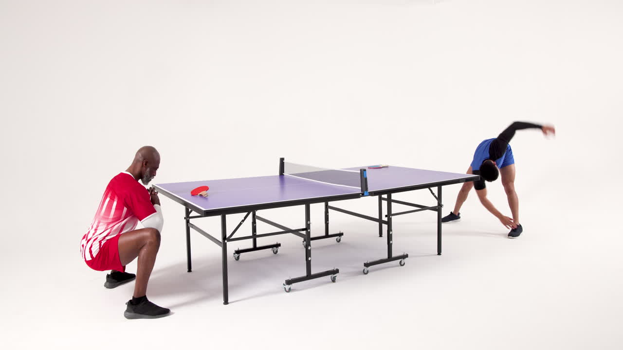 Playing table tennis, two men competing intensely in studio setting