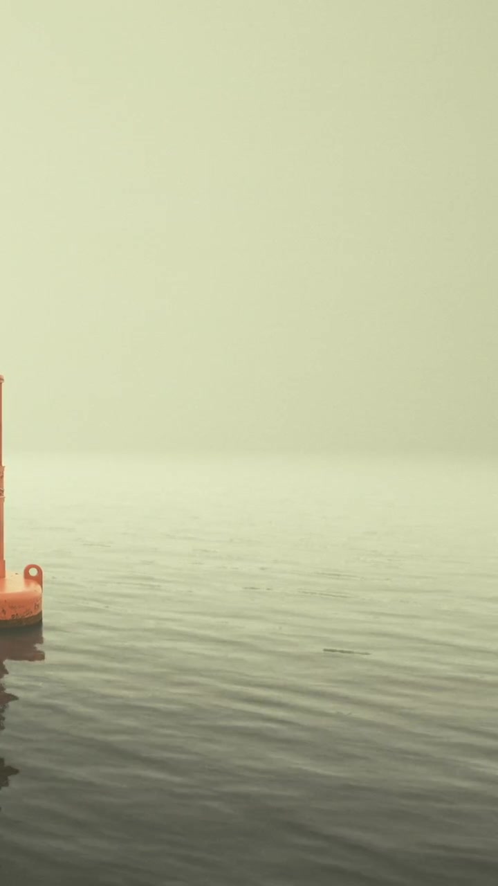 Calm waters embrace a solitary buoy under a serene misty sky
