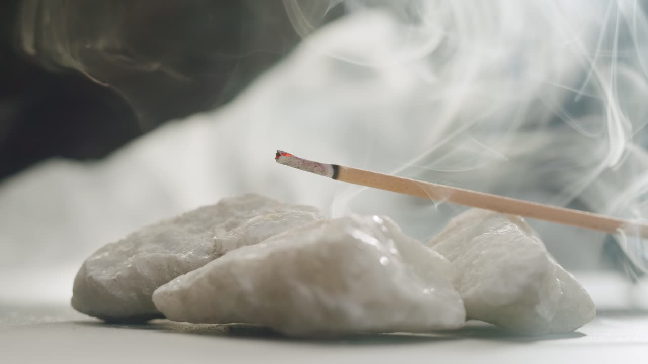 Person holding Palo Santo wood stick in hand, aromatic Palo Santo burning on black background, smoke spreading around, slow motion video clip, high quality 4k close up footage. High quality 4k footage