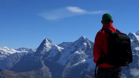man in red coat enjoys the wonderful views and mountains of jungfraujoch, known as top of europe