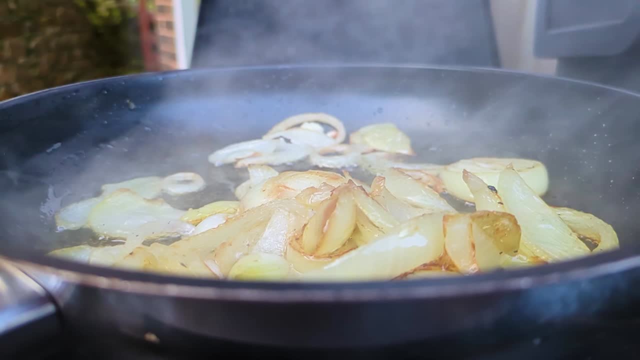 바에 있는 뜨거운 팬에서 양파가 증기와 함께 어지고 있습니다.